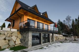 a house with a balcony on top of a stone wall at Tatres Bachledówka in Czerwienne