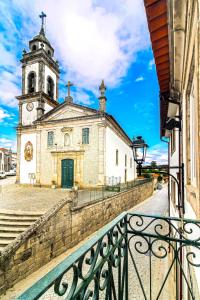 una vieja iglesia con una torre de reloj en una calle en Refúgio Rústico - Exclusivo, en Favaios
