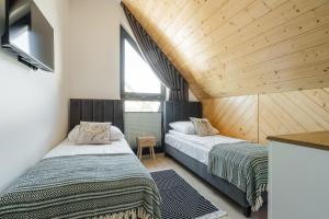 two beds in a room with wooden ceilings at Tatres Bachledówka in Czerwienne