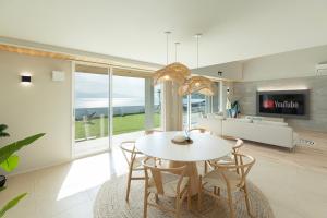 una sala da pranzo con tavolo e sedie bianchi di Hale Moana a Itoshima