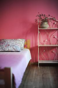 a pink bedroom with a bed and a shelf with a potted plant at Apartments Life & Energy in Čatež ob Savi