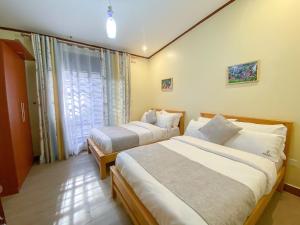 a hotel room with two beds and a window at Maison Princeton in Kampala