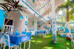 Viik wellness inn -3 Star Resort in Arambol Beach في أرامبول: غرفة بها طاولات وكراسي زرقاء وشجرة نخيل