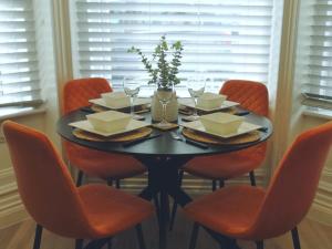 a dining room table with orange chairs and a black table with wine glasses at Stunning Modern Apartment Sleeps 4 - 6 Min walk from Golden Beaches-Free Parking in Bournemouth