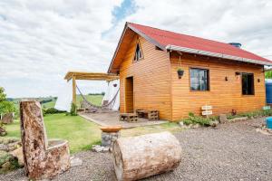 una casa de madera con una tienda de campaña y algunos troncos en Chico Cabanas, en Lajeado Grande