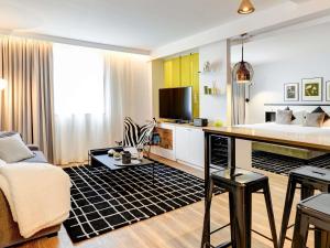 uma sala de estar com um sofá e uma televisão em Novotel Paris Centre Bercy em Paris mais 100 fotografias