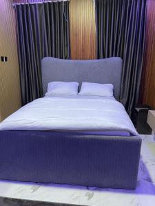 Una cama grande con cabecero morado en un dormitorio. en LEKKI CONSERVATION FURNiSHED APARTMENT 1, en Lagos