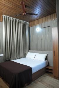 Grand sapphire 100 meters from Sub urban Bus stand Mysore في ميسور: غرفة نوم بسرير كبير مع ستارة