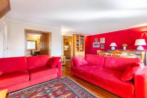 a living room with two red couches and a kitchen at Hostdomus - Rooftop Deluxe Suite in Sestriere +31 photos