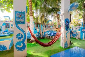 Viik wellness inn -3 Star Resort in Arambol Beach في أرامبول: غرفة بها أرجوحة وطاولة وكراسي