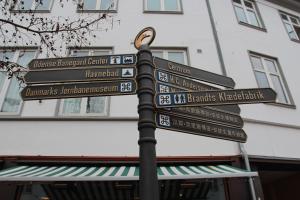 a street sign with directions to different cities at The Cozy Cave Odense Center in Odense