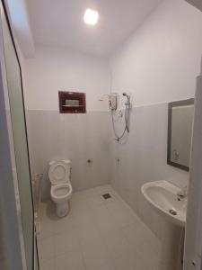 a white bathroom with a toilet and a sink at villa Calm Haven in Unawatuna