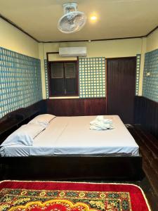 a bedroom with a bed with a rug and a window at Friendship Guesthouse Dondet in Nakasong