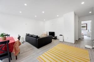 a living room with a black couch and a yellow rug at T4 Furadouro with sea view in Ovar