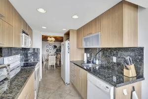 een keuken met marmeren aanrechtbladen en houten kasten bij Luxury Two-Bedroom Oceanfront Apartment With Panoramic Views in South Palm Beach