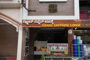 Grand sapphire 100 meters from Sub urban Bus stand Mysore في ميسور: متجر يحمل لافتة مكتوب عليها "نزل المفاجأة الكبرى"