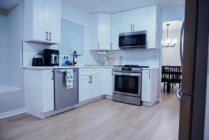 Jacuzzi Cul de Sac Home في Country Club Hills: مطبخ بخزائن بيضاء وموقد وميكروويف +11 صورة