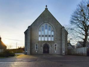 uma grande igreja de tijolos com uma cruz em cima em Turfhill House em New Deer