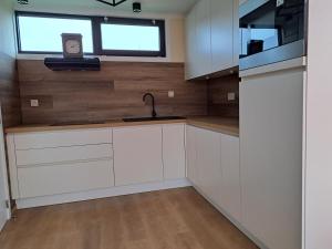 a kitchen with white cabinets and a sink and a window at Jonckershof Middelkerke bungalow 26 in Middelkerke