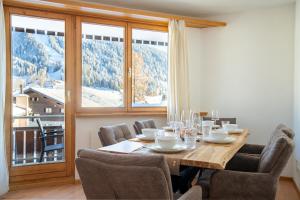 Un comedor con una mesa y un gran ventanal. en A&Y Alpenchique Apartment Davos, en Davos