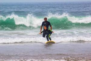 Tamazirt Surf Shop & School في تغازوت: شخصان يقفان على لوح ركوب الأمواج في المحيط