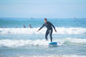 Tamazirt Surf Shop & School في تغازوت: رجل يركب موجة على لوح ركوب الأمواج في المحيط