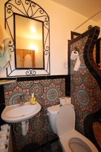 Un baño con lavabo, inodoro y espejo. en Maison d'Hôte Argana, en Aït Idaïr 62 fotos más