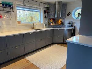 a kitchen with blue cabinets and a sink and a window at Lovely view & walking distance to the beach SE09150 in Svanesund +26 photos