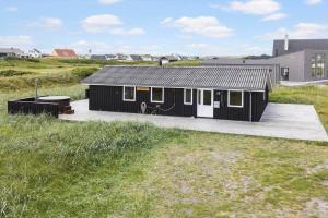 a black house with a deck in a field at 525-Vestervig-Spovevej-5 in Vestervig