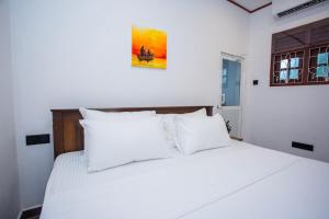 een slaapkamer met een wit bed met witte kussens bij jenul villa in Ahangama