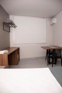 a room with a table and a white wall at Oscar flats in Montes Claros