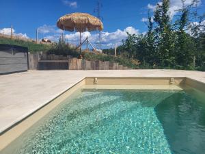 a swimming pool with an umbrella next to a patio at Domaine des Granges in La Bâtie-Montgascon