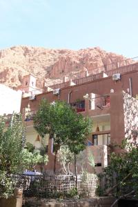 un edificio con árboles frente a una montaña en Maison d'Hôte Argana, en Aït Idaïr