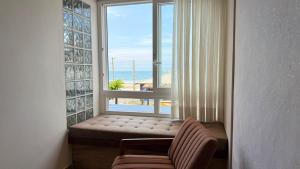 a window seat in a room with a view of the ocean at Pousada Gamboa estações in Garopaba