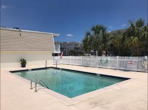 a swimming pool in front of a white fence at Sanderling - Pet Friendly - Walk to Beach - Pool! in Holden Beach