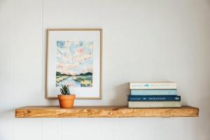 a shelf with books and a picture and a plant at Sanderling - Pet Friendly - Walk to Beach - Pool! in Holden Beach