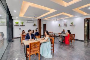 FabHotel Groom Room في نويدا: مجموعة من الأشخاص يجلسون على الطاولات في مطعم