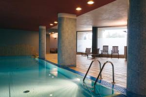 een zwembad met stoelen en tafels in een gebouw bij Grey Apartment Kołowa in Krakau