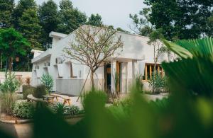 een wit huis met een boom ervoor bij Nong Lam Ecolodge in Linh Xuân Thôn