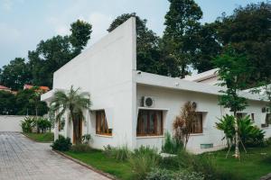 a white house with trees in the background at Nong Lam Ecolodge in Linh Xuân Thôn