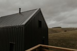 un edificio nero su una collina con un campo di Aux Choses Simples  Altre 14 foto