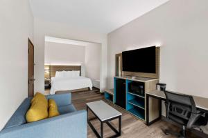 Sonesta Essential Beaumont في بومونت: غرفة فندق بسرير واريكة زرقاء