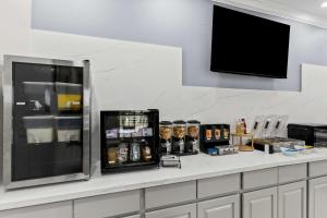 Sonesta Essential Beaumont في بومونت: مطبخ مع كونتر مع ثلاجة ومشروبات