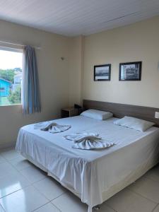 a bedroom with a bed with white sheets and a window at Hotel Mirante Da Ilha in Alter do Chao