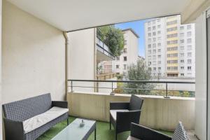 Un balcón con sillas y mesas y un gran ventanal. en Superbe 90M2, chic & cosy avec Parking privé et Terrasse - 10pers, en Villeurbanne
