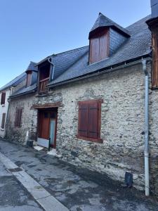 an old stone building with wooden doors on a street at Grange des Taouré in Vignec