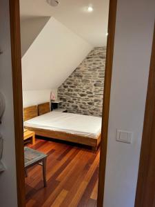 a bedroom with a bed and a stone wall at Grange des Taouré in Vignec