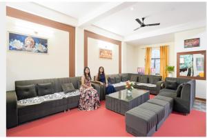 two women sitting on couches in a living room at FabHotel SP 97 in Indore