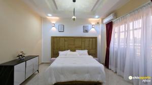 a bedroom with a large white bed and a window at Chic & spacious studio with parking in Yaoundé