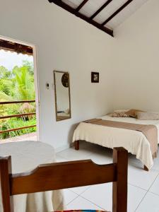 two beds in a white room with a window at Mandacaru Pousada in Porto Seguro